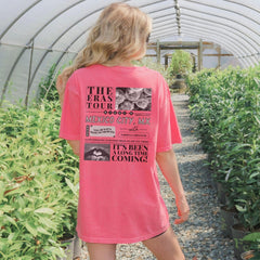 a woman in a pink shirt is walking through a greenhouse