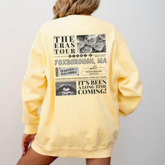 a woman wearing a yellow sweatshirt with the words the eras tour on it