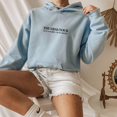 a woman sitting on a toilet wearing a blue hoodie