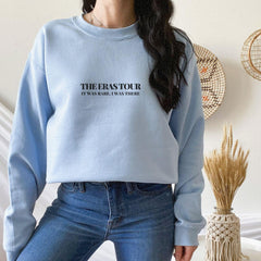 a woman wearing a blue sweatshirt with the words the eras on it