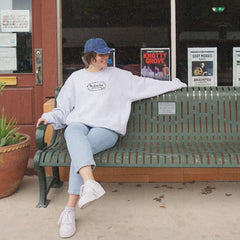 a woman sitting on a bench in front of a book store