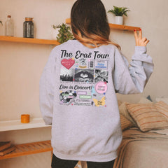 a woman standing in front of a bed wearing a gray sweatshirt