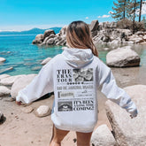 a woman in a white hoodie walking on a beach