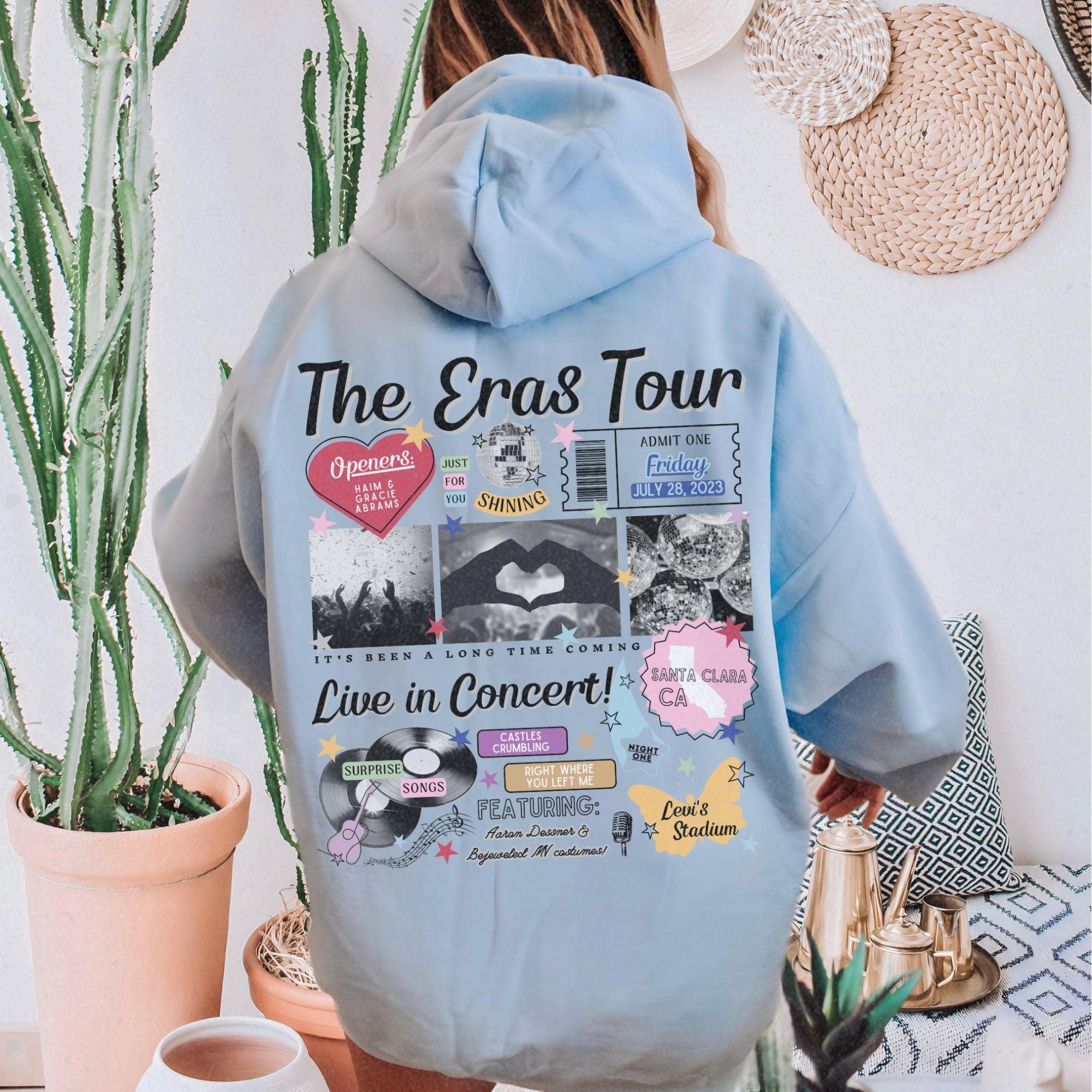 a woman wearing a blue hoodie with the words the eras tour on it