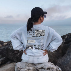a woman sitting on a rock looking out at the ocean
