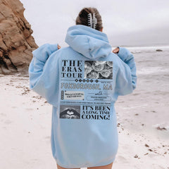 a person standing on a beach wearing a blue hoodie