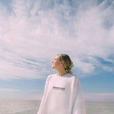 a woman standing on a beach looking up at the sky