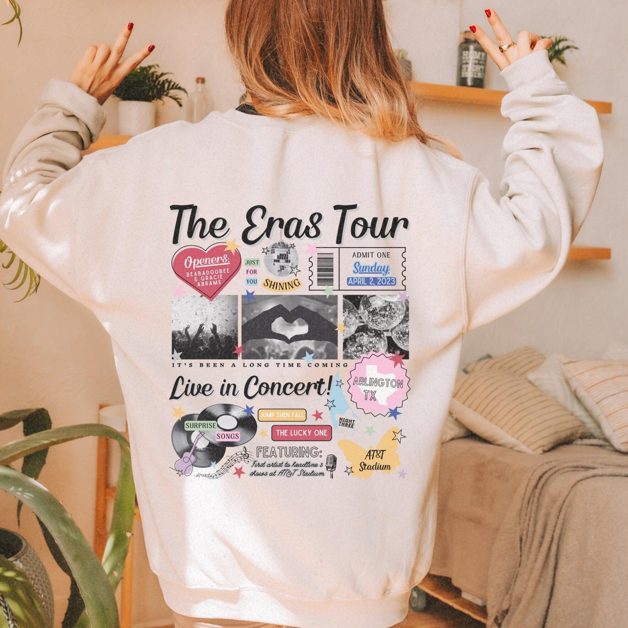a woman wearing a white sweatshirt with the words the eras tour printed on it
