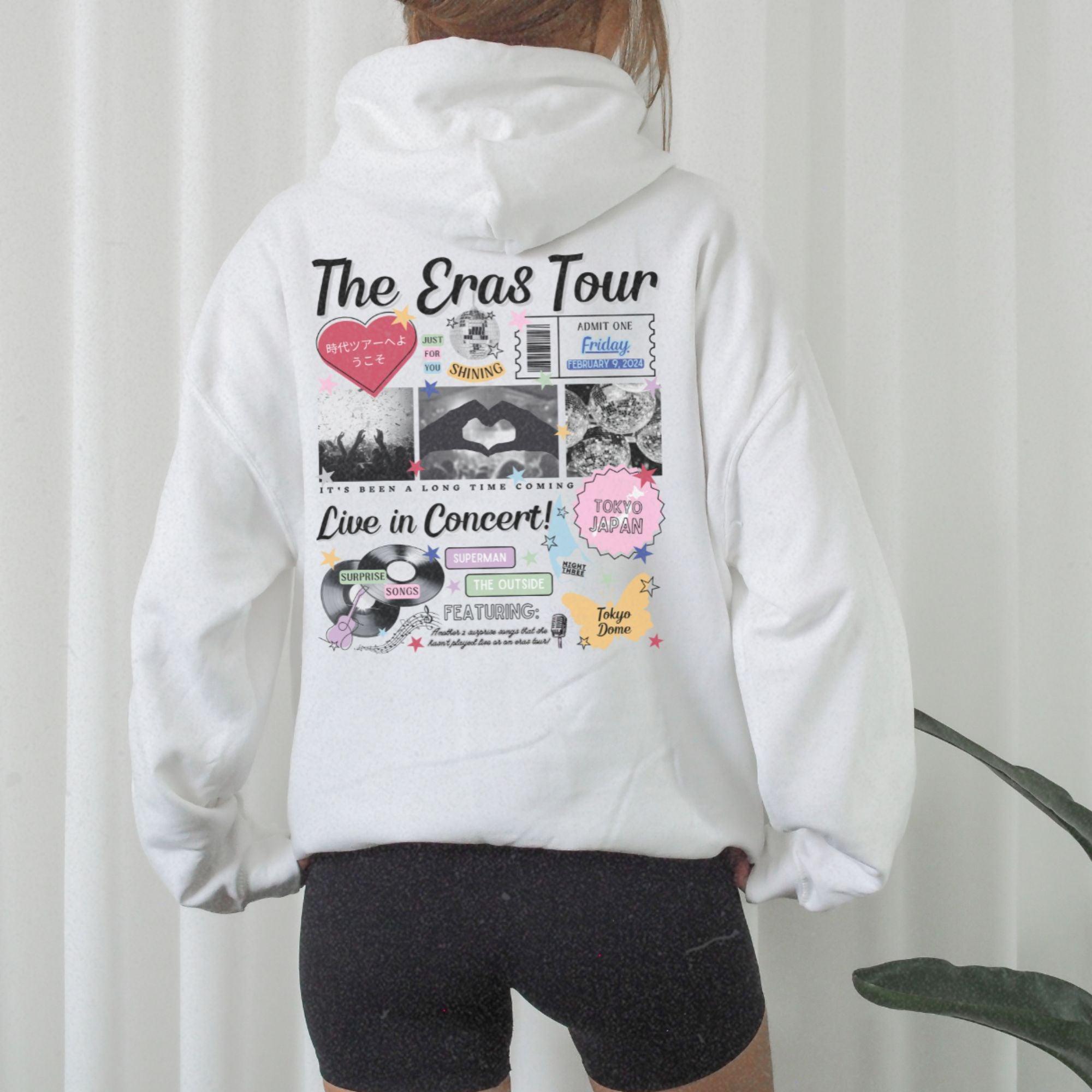 a woman wearing a white hoodie with the words the eras tour printed on it