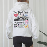 a woman wearing a white hoodie with the words the eras tour printed on it