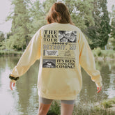 a woman in a yellow sweatshirt is walking by the water