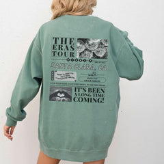 a woman wearing a green sweatshirt with a tour poster on it