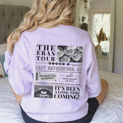 a woman sitting on top of a bed wearing a sweatshirt