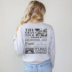 a woman wearing a grey sweatshirt with a tour poster on it