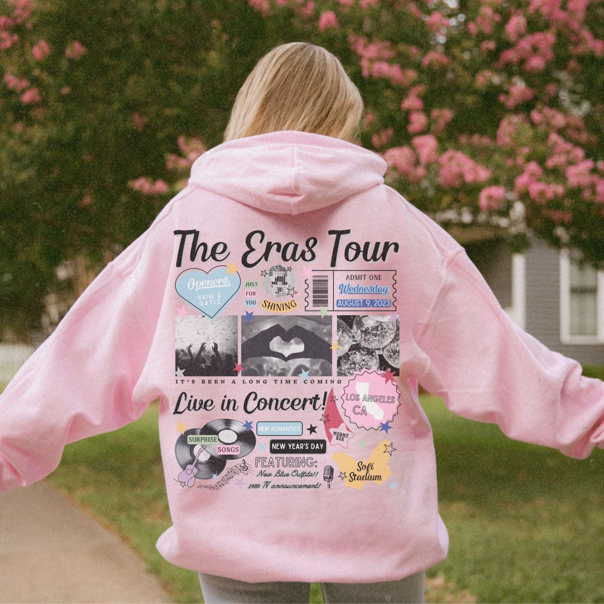 a girl in a pink hoodie with the words the eras tour on it