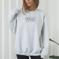 a woman wearing a grey sweatshirt with the words the great tour on it