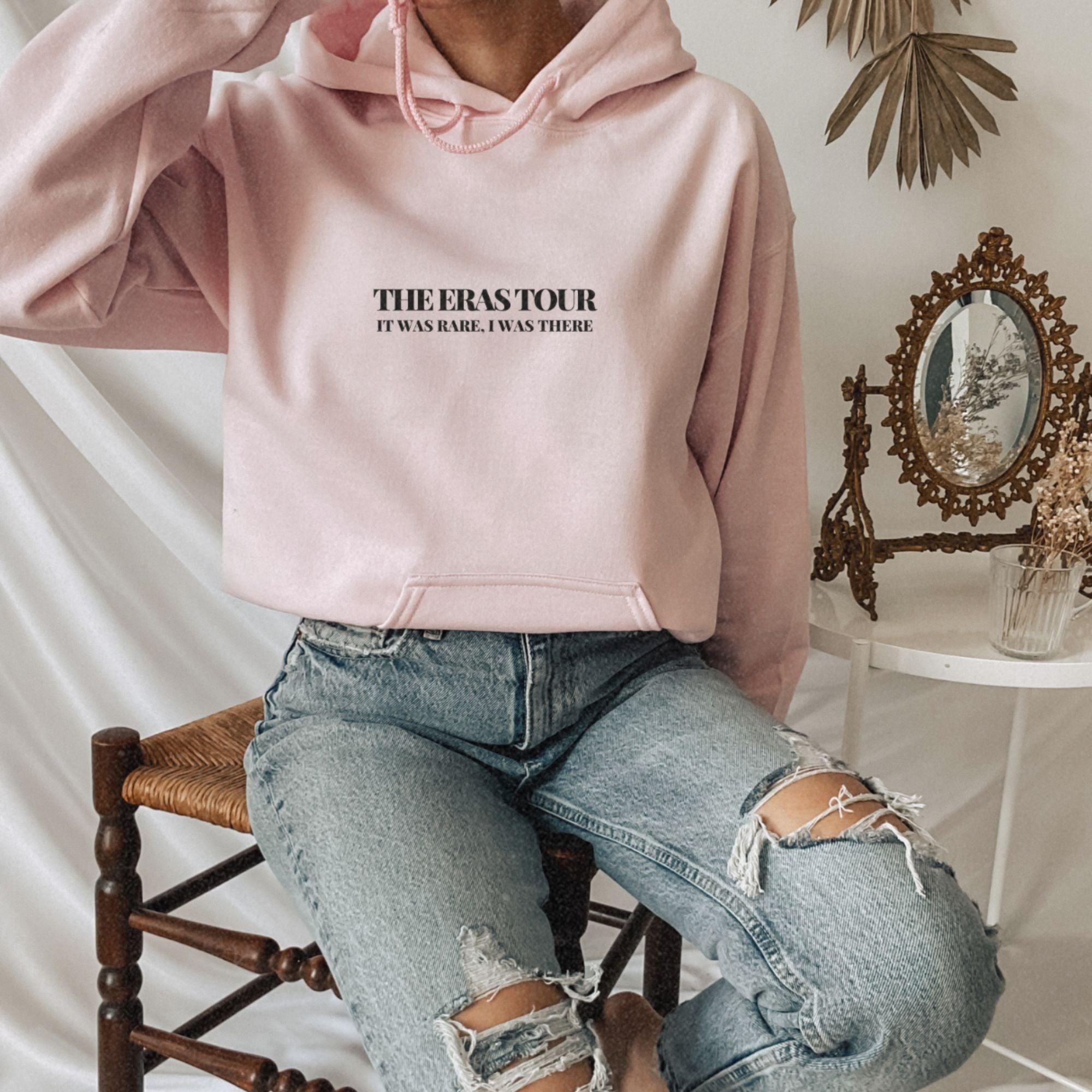 a woman sitting on a chair wearing a pink hoodie