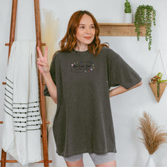 a woman standing in front of a wall holding a peace sign