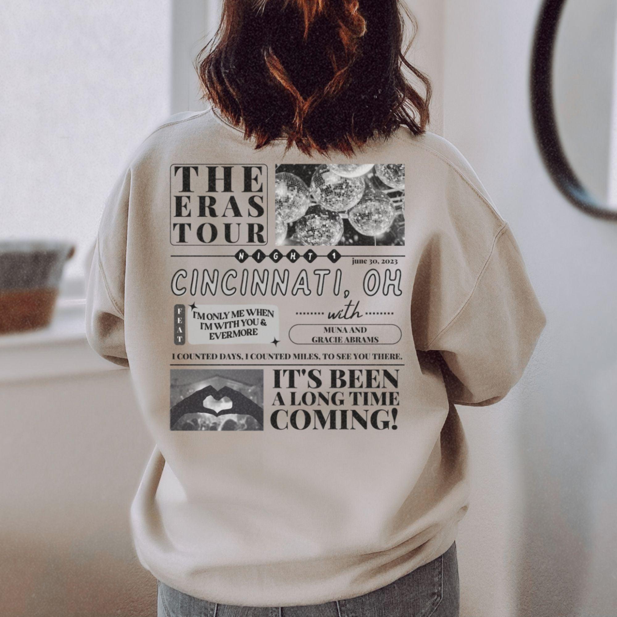 a woman standing in front of a window wearing a sweatshirt