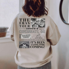 a woman standing in front of a window wearing a sweatshirt