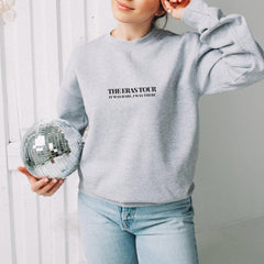 a woman in a grey sweatshirt holding a disco ball