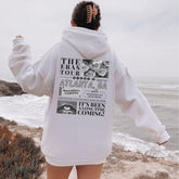 a person standing on a beach with a hoodie on