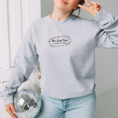 a woman in a grey sweatshirt holding a disco ball