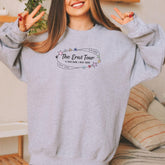 a woman wearing a grey sweatshirt with the words the east tour written on it