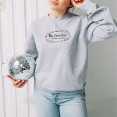 a woman in a grey sweatshirt holding a disco ball
