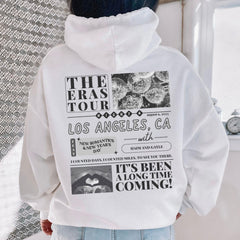 a person wearing a white hoodie with the words the eras tour printed on it