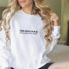 a woman sitting on a bed wearing a white sweatshirt