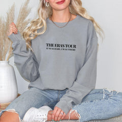 a woman sitting on a bed wearing a sweatshirt