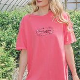 a woman in a pink shirt is standing in a greenhouse