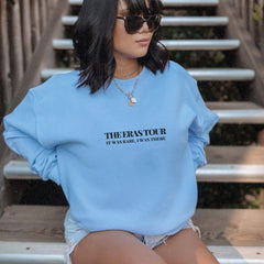 a woman in a blue sweatshirt sitting on some steps
