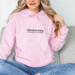 a woman sitting on a couch wearing a pink sweatshirt