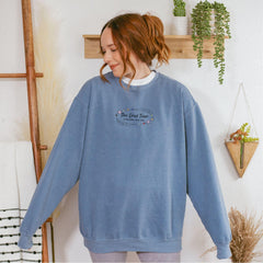 a woman standing in front of a wall wearing a blue sweatshirt