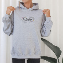 a woman wearing a grey hoodie with the words the great tour on it