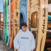a man standing in front of a row of surfboards
