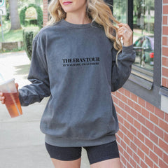 a woman is holding a drink and wearing a sweatshirt
