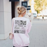 a woman walking down a street holding a small dog