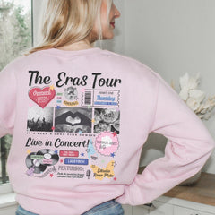 a woman wearing a pink sweatshirt with the words the eras tour on it