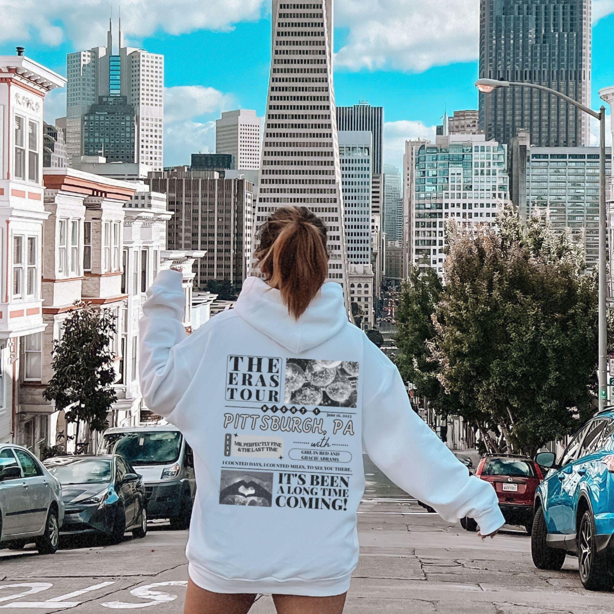a woman in a white hoodie is walking down the street