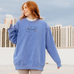 a woman in a blue sweatshirt holding a cup of coffee