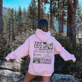 a woman in a pink hoodie standing in the woods