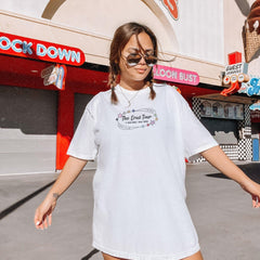 a woman in a white dress and sunglasses walking down a street