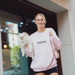 a woman is holding a small white dog