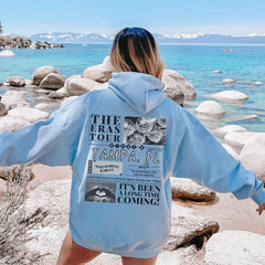a woman in a blue hoodie standing on a beach