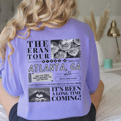 a woman sitting on a bed wearing a purple shirt