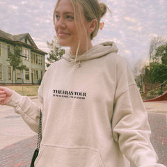 a woman in a white hoodie holding a cell phone