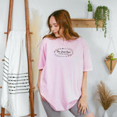 a woman standing in front of a wall wearing a pink shirt